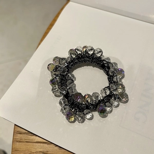 Detailed macro view of minimalist crystal beaded elastic hair tie on a neutral background