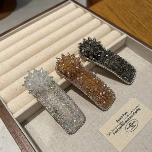 Detailed shot of three crystal hair clips in champagne and gray on velvet tray