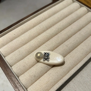 Close-up of a cream-colored hair clip with a silver zircon bear and a golden bead