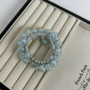 Detailed close-up of blue iridescent beads on a stylish bunched elastic hair scrunchie