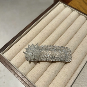 Macro detail of a crystal flower hair clip with clear beads in a beige velvet gift box