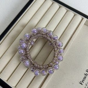 Close-up of purple iridescent beads and champagne elastic hair tie on jewelry tray
