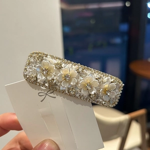 Elegant floral hair clip with white resin flowers and rhinestones on a metal base