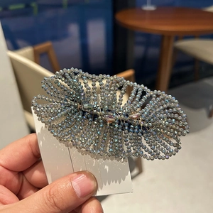 Close-up of woven blue and grey crystal beads on a leaf-shaped hair clip with elegant shine