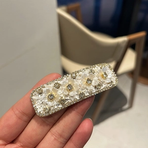 Elegant floral rhinestone pearl hair clip with four white petals on a golden metal base