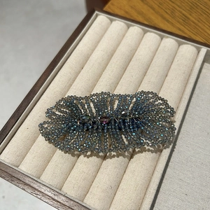 Detail showing handcrafted dark grey-blue crystal beads and woven texture on hair clip