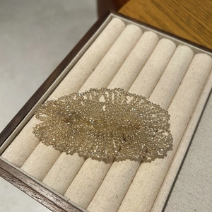 Macro detail of handmade woven champagne crystal beads on an elegant hair clip