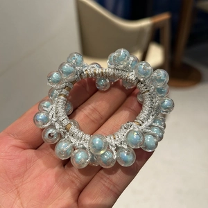 Detail of light blue iridescent beads on a silver elastic hair tie and wrist accessory
