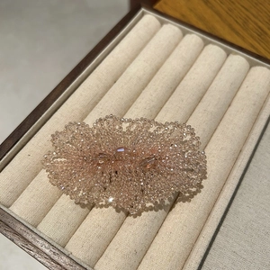 Detail view of handmade champagne crystal flower hair clip with sparkling beaded petals