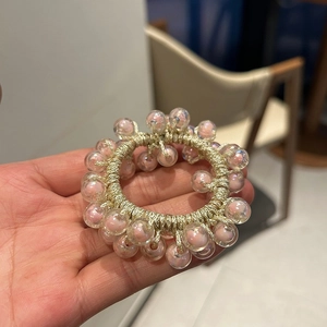 Close-up of vibrant jelly beads with iridescent coating on champagne braided elastic hair tie