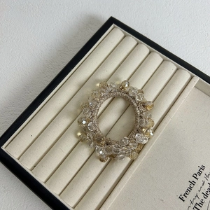 Elegant champagne crystal beaded hair tie on a velvet tray with a floral wreath design
