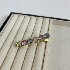 Detail view of premium hair clip with six multicolored oval crystals on velvet tray