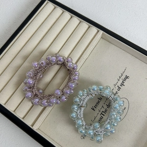 Detailed macro shot of lavender and light blue aurora bead hair ties on a jewelry tray
