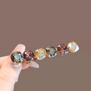 Detailed close-up of crystal barrette with six square-cut purple and warm stones