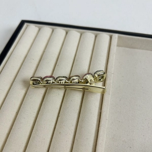 Elegant gold duckbill hair clip featuring five faceted pink crystals on a velvet tray