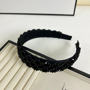 Détail d'un serre-tête large noir orné de perles en cristal sur base en tissu