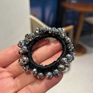 Macro detail of elastic hair tie with dark grey faceted crystal beads and metallic finish