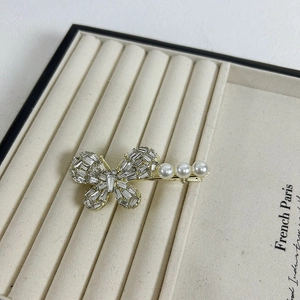 Elegant gold butterfly hair clip with sparkling rhinestones and white pearls on velvet tray