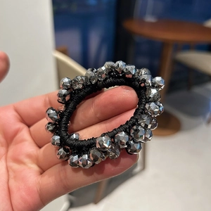 Detailed macro view of crystal hair tie with shiny faceted beads held in hand