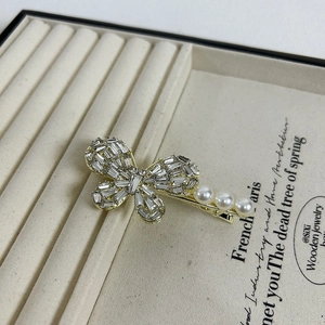 Macro detail of bow-shaped hair clip with sparkling zircons and delicate white pearls