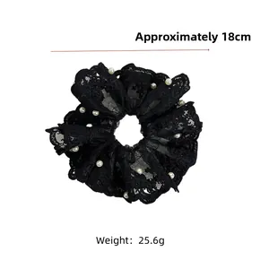 Détail d'un chouchou en dentelle noire avec perles et mesure de diamètre de 18 cm