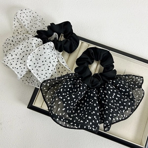 Detail of oversized polka dot scrunchies with bow design on a luxury display tray