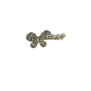 Elegant gold bow hair clip with zircon rhinestones and pearls on a white background