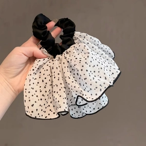 Detailed close-up of a white pleated tulle scrunchie with black polka dots and wavy edges