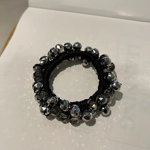 Detailed macro view of black elastic hair tie with faceted silver crystal beads