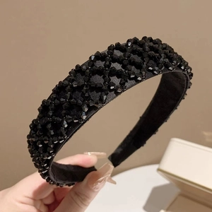 Détail d'un serre-tête large noir avec des perles facettées et une finition en satin