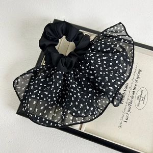 Detail of a French style black polka dot organza hair scrunchie in a white display box