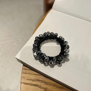 Close-up of beaded hair tie with reflective silver crystal beads on open book