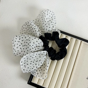 Detailed close-up of a French style polka dot mesh bow hair scrunchie on a display tray