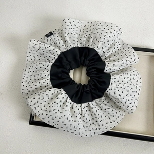 Polka dot scrunchie with black and white pleated fabric on a minimalist white background