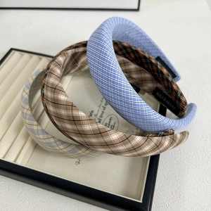 Détail de trois serre-têtes rembourrés à carreaux en tissu bleu, café et gris clair