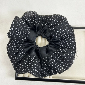 Detail of a large black and white polka dot scrunchie on a white display tray