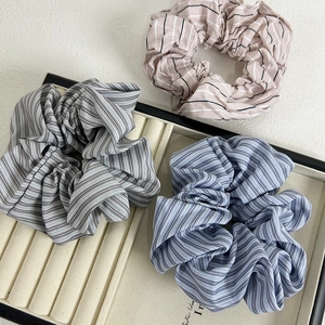 Three-piece set of striped high-count cotton hair scrunchies in pastel tones on a cream tray