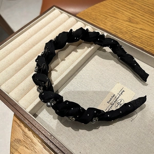 Detailed macro view of black woven headband with tiny silver beads on a jewelry display tray