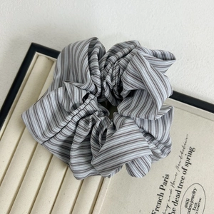 Detail of a gray and white striped fabric scrunchie in a premium jewelry display box