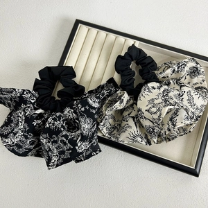 Close-up of black and white Toile de Jouy floral chiffon scrunchies set on jewelry tray