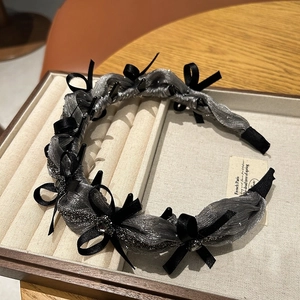 Close-up of charcoal fabric headband with satin bows and sparkling rhinestones on jewelry tray