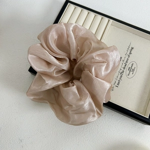 Détail d'un grand chouchou en satin rose champagne avec texture perlée et plis doux