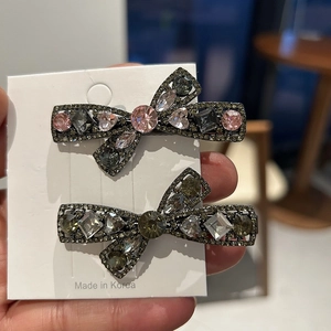 Macro detail of two sparkling rhinestone bow hair clips with pink and grey crystal accents