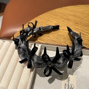 Detail of grey pleated headband with black satin bows and dark crystal accents