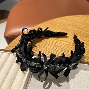 Detail of black satin ribbon bow headband with shimmering silver trim and heart rhinestones