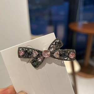 Elegant rhinestone bow hair clip with pink and grey crystals on a display card