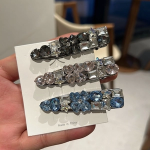 Close-up of three sparkling rhinestone hair clips in heart, star and geometric shapes