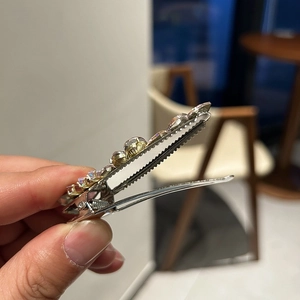Detailed close-up of a silver alloy hair clip with pink and champagne rhinestones