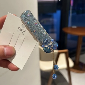 Pince à cheveux étincelante en strass bleus avec breloque fleurie et gland doré