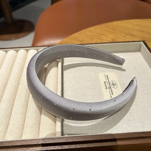 Elegant grey satin sponge headband with silver rhinestones on a jewelry tray